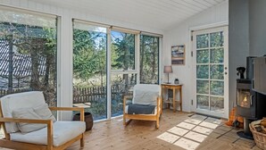Une pièce chaleureuse avec une cheminée, des meubles en bois et de grandes fenêtres donnant sur l’extérieur.