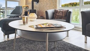 Una sala de estar moderna con una mesa redonda, dos sillones, un sofá y una chimenea.