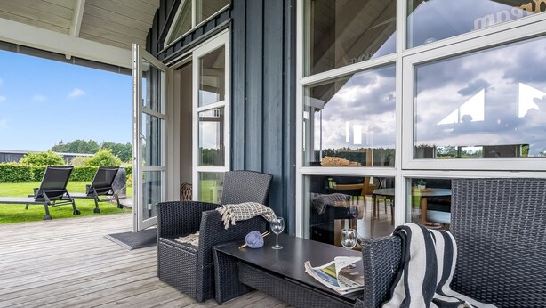 Un espace extérieur abrité, aménagé avec des meubles en osier, une table et un journal.