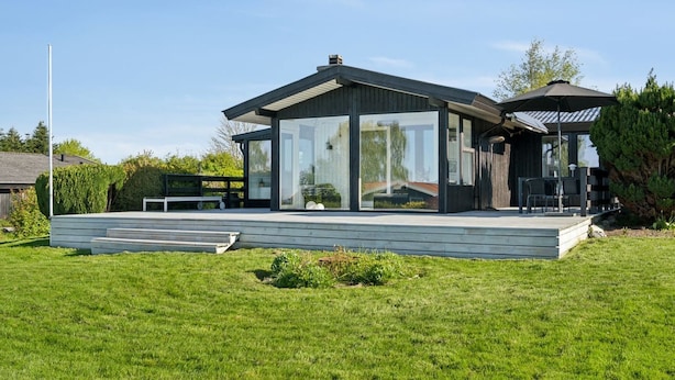 Une maison moderne dotée de grandes baies vitrées, d’une terrasse et d’un espace patio.