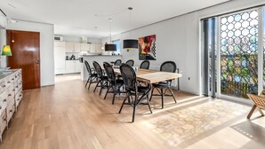 A modern kitchen with white cabinets, a dining area with a wooden table and black chairs, and a large glass door leading to a garden. - "Hilppa" - 400m from the sea by Interhome (Harboøre)