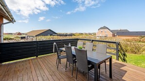 A wooden deck with a table and chairs, overlooking a residential area with houses and a clear sky. - "Hilppa" - 400m from the sea by Interhome (Harboøre)