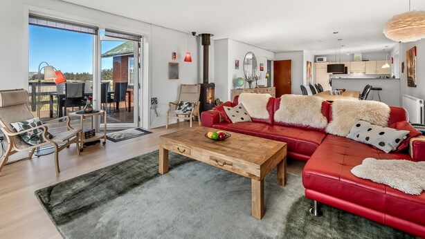 A modern living room with a red sofa, wooden coffee table, and a view of the outdoors. - "Hilppa" - 400m from the sea by Interhome (Harboøre)