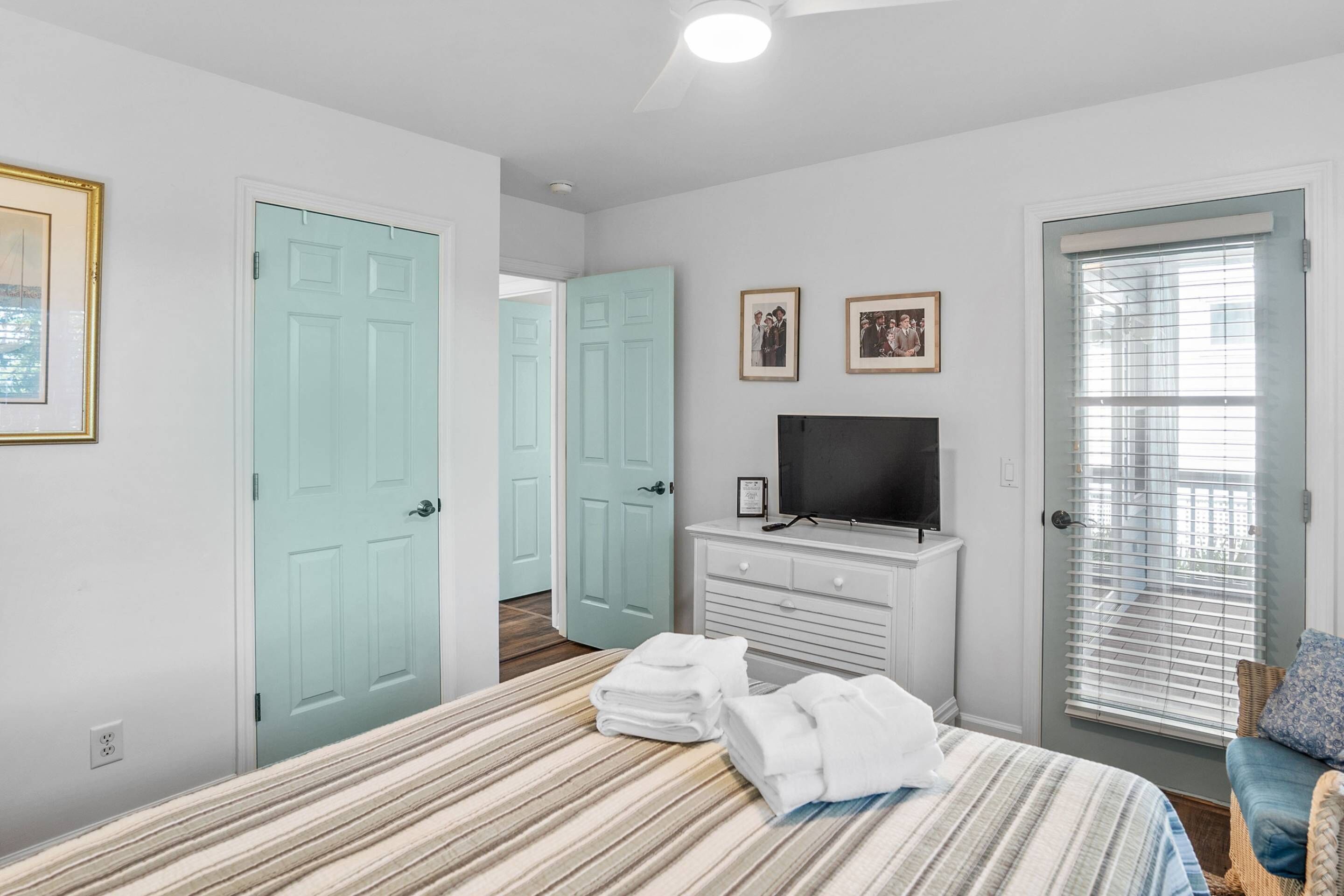 A bedroom with a bed, a TV, a dresser, and a door.