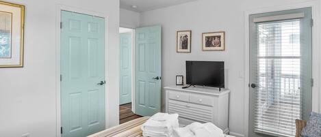 A bedroom with a bed, a TV, a dresser, and a door.