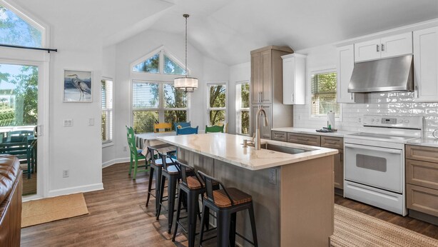 Una cocina moderna con una isla grande, taburetes de bar y un comedor con sillas.