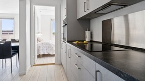 A modern kitchen with grey cabinets, a black countertop, and a stainless steel range hood.