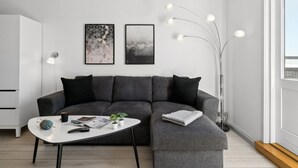 A modern living room with a grey sectional sofa, a white coffee table, and two framed artworks on the wall.