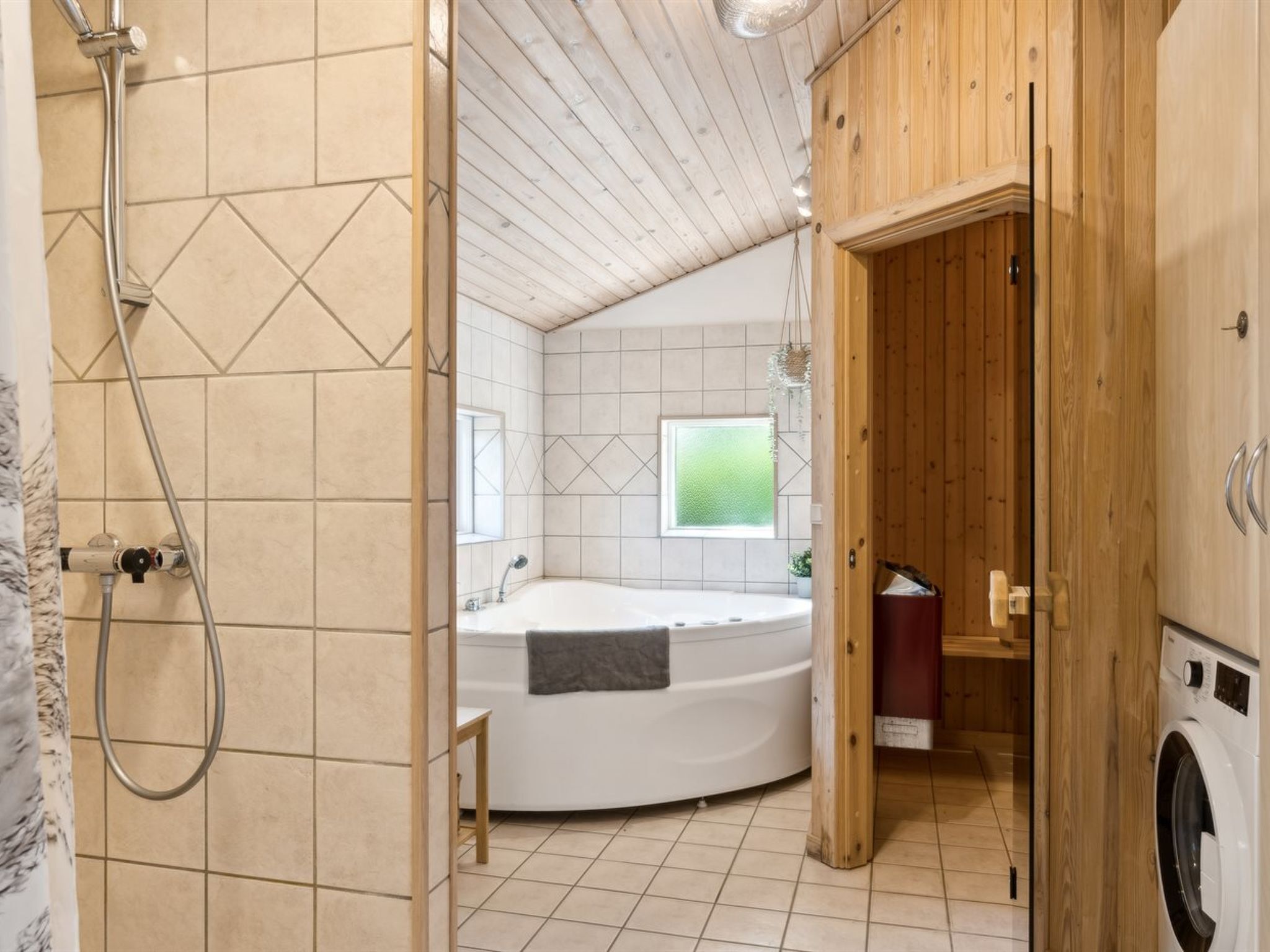 A bathroom with a shower, a bathtub, and a washing machine.