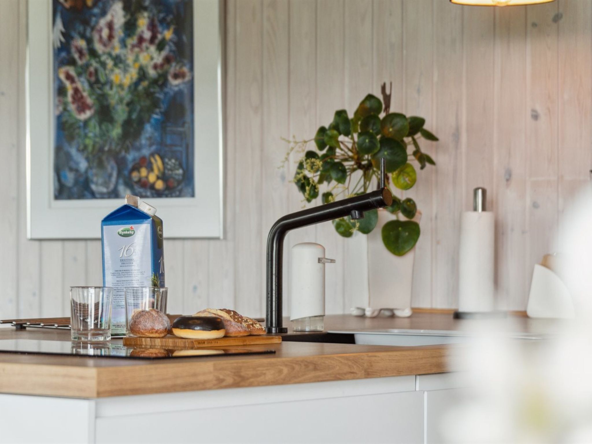 A kitchen counter with a milk carton, a glass, and pastries.