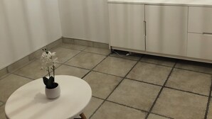 A room with a white cabinet, a small table with a potted plant, and a lamp on top of the cabinet. - Charming house (Remoulins)
