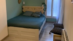 A bedroom with a bed, a bedside table, a window, and a radiator. - Charming house (Remoulins)