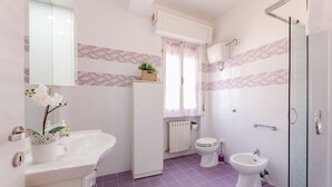 Une salle de bain avec un lavabo blanc, des toilettes, un bidet et un espace douche.