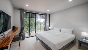 Quarto de hotel moderno com uma cama grande, uma escrivaninha e uma televisão.