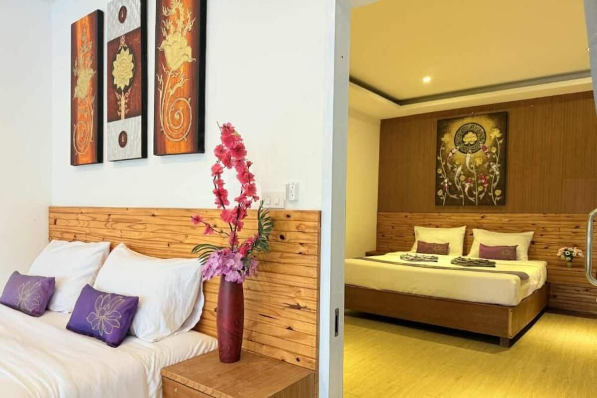 A bedroom with a wooden headboard, a bed with white bedding, a nightstand, and a vase with flowers.