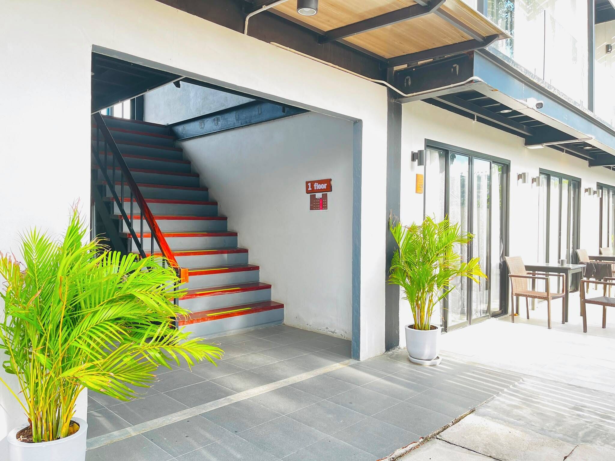 A staircase leading to the first floor, potted plants, and a seating area with tables and chairs.