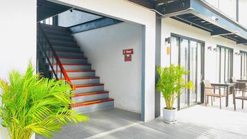 A staircase leading to the first floor, potted plants, and a seating area with tables and chairs.