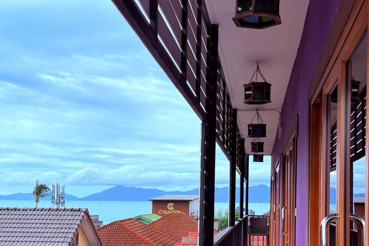 A balcony with a view of the sea and mountains, featuring a tiled floor and a railing.