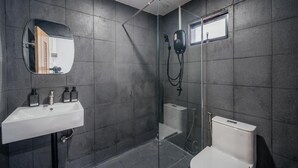 Uma casa de banho moderna com chuveiro envidraçado, uma sanita e uma pia branca com dispensadores de sabão.