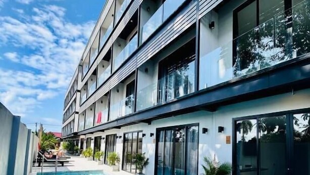 Um edifício moderno com piscina, janelas amplas e céu claro.