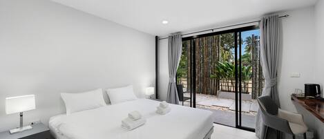 Una habitación de hotel moderna con una cama grande, un escritorio y vistas al exterior.