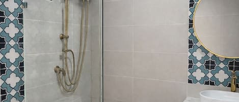 Un baño con ducha de vidrio, inodoro blanco y lavabo con espejo.