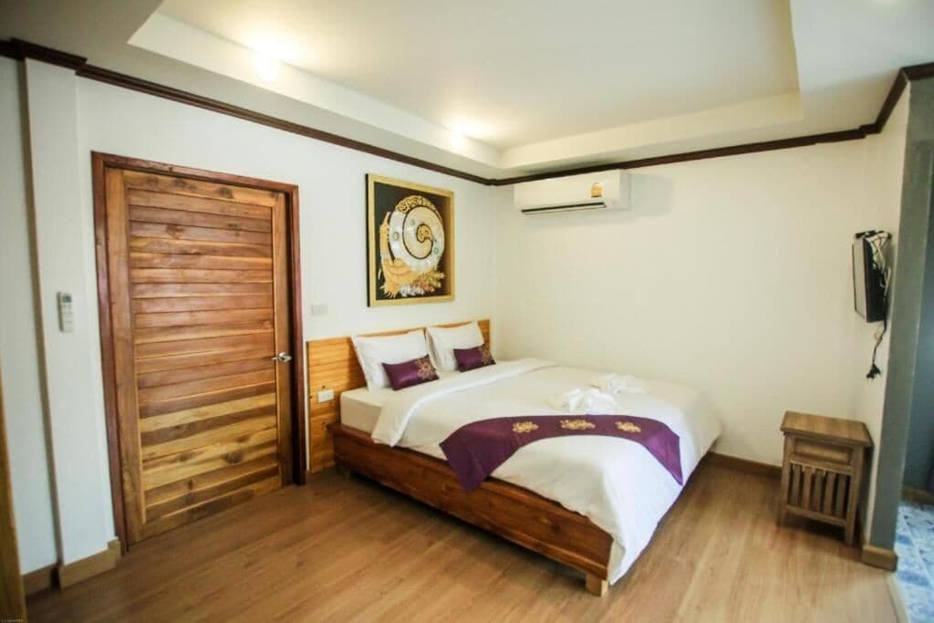 Un dormitorio con cama de madera, aire acondicionado de pared y puerta con diseño de paneles de madera.
