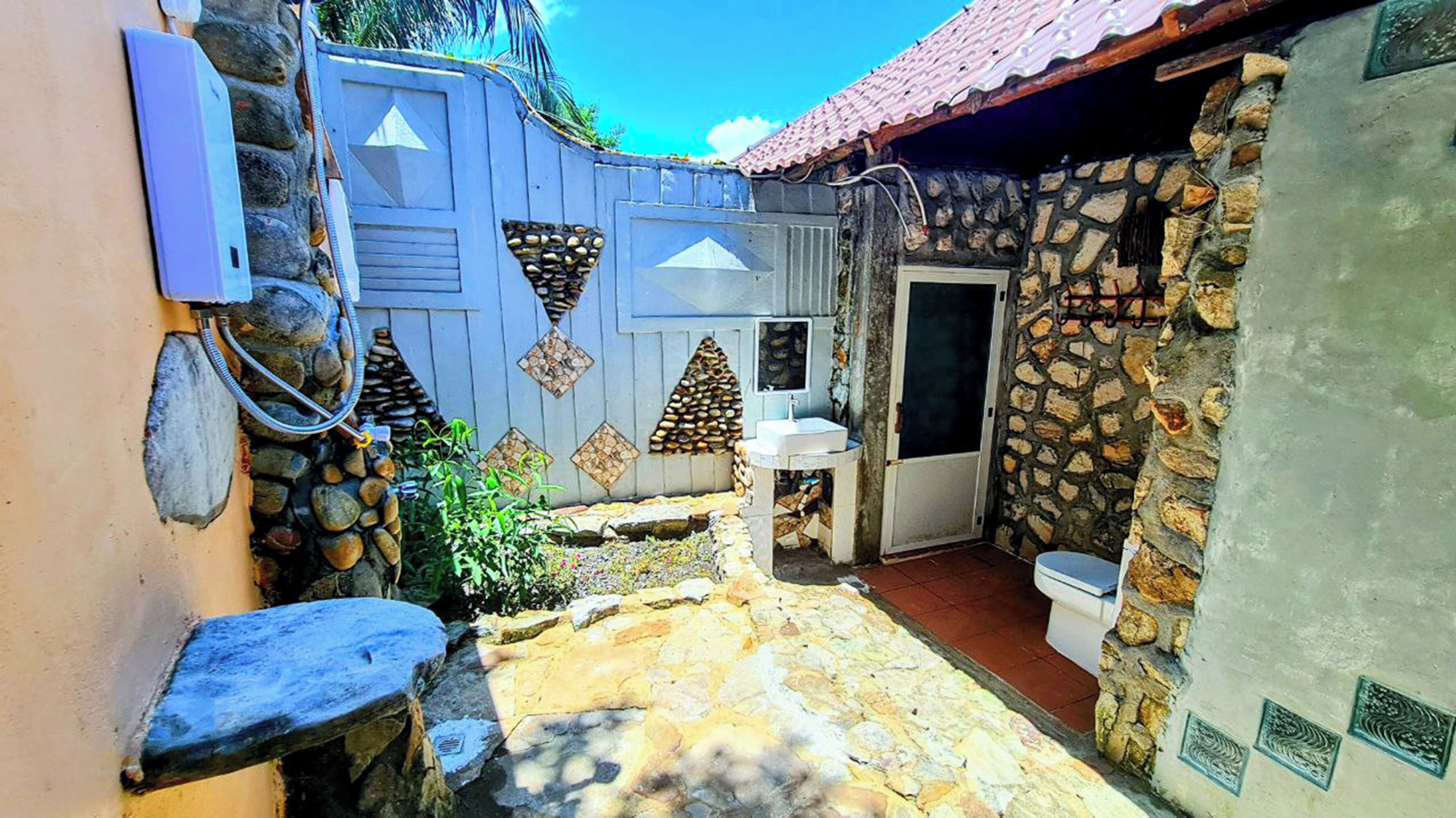 A stone-walled bathroom with a toilet and a sink.