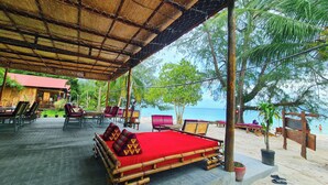 A beachside lounge with bamboo furniture, a red cushioned sofa, and a view of the sea. - Europe Enchanted Bungalow Koh Rong (Koh Rong)