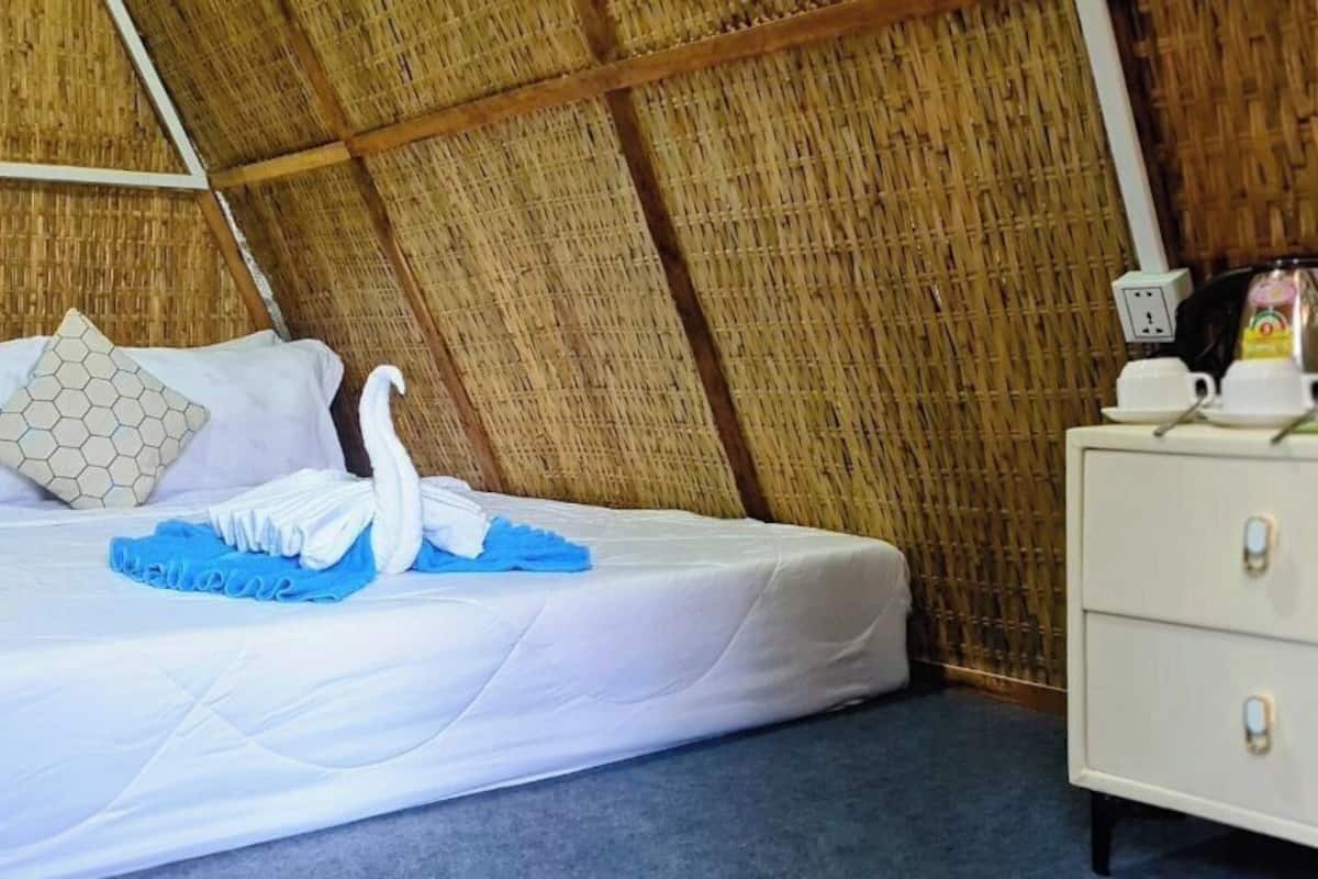 A room with a bed, a white dresser, and a bamboo wall.