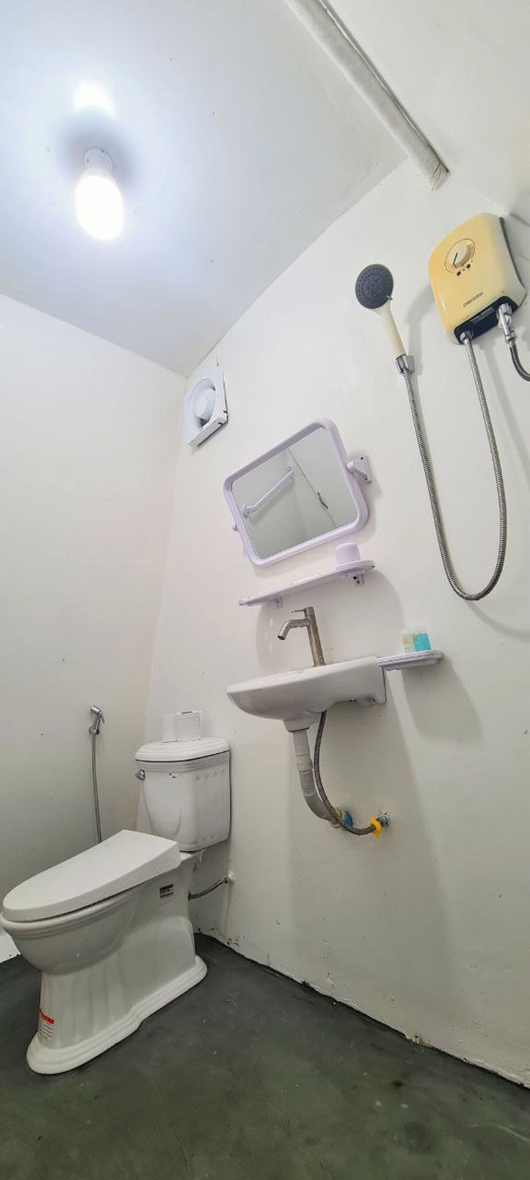 A small, basic bathroom with a toilet, sink, and shower.
