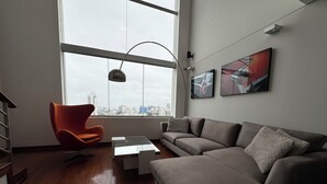 Un salon moderne avec une grande fenêtre, un canapé, un fauteuil et une table basse.
