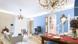 A living room with a dining area, a chandelier, a television, and a staircase. - Easylife - Sophisticated apartment with terrace (Milano)