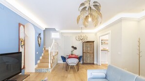 A living room with a TV, sofa, dining table, chairs, and a staircase. - Easylife - Sophisticated apartment with terrace (Milano)