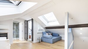 A spacious loft with a high ceiling, skylights, a blue sofa, and a small table. - Easylife - Sophisticated apartment with terrace (Milano)