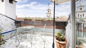 A balcony with a metal table and chairs, potted plants, and a view of a tower in the background. - Easylife - Sophisticated apartment with terrace (Milano)