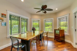 A dining area with a wooden table, chairs, a ceiling fan, and a television. - Gateway to the Gunks: Winery Walks & Rock Walls (Gardiner)
