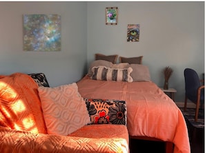 A bedroom with a bed, a sofa, and two wall-mounted paintings. - Gateway to the Gunks: Winery Walks & Rock Walls (Gardiner)