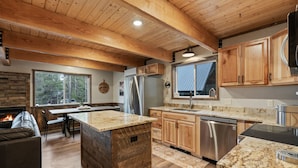 Una cocina moderna con armarios de madera, encimeras de granito y electrodomésticos de acero inoxidable, además de una isla grande.