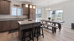 Una cocina moderna con encimeras de granito, armarios de madera oscura y una isla central con taburetes.