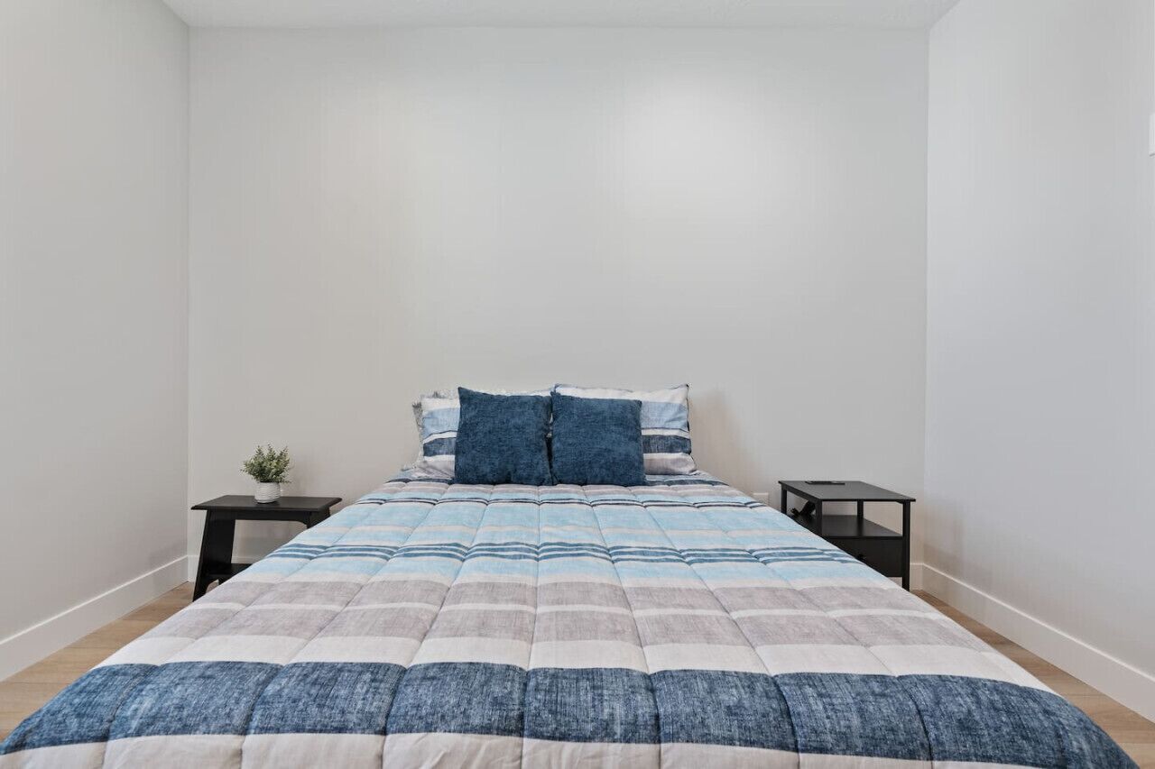 Ein Schlafzimmer mit einem Bett, zwei Nachttischen und einer kleinen Pflanze.