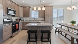 Una cocina moderna con encimeras de granito, electrodomésticos de acero inoxidable y armarios de madera.
