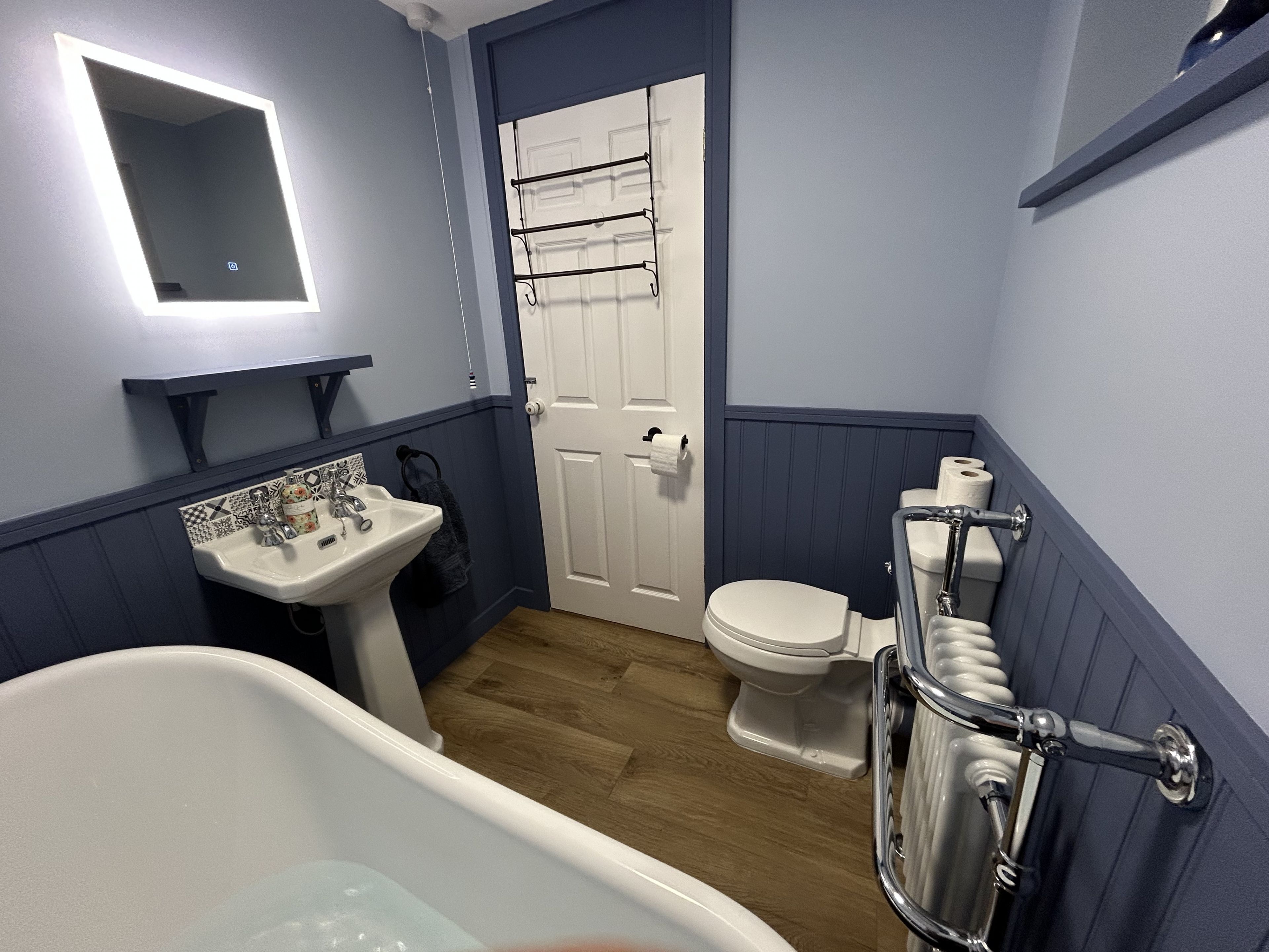 A bathroom with a white bathtub, a white toilet, and a sink with a mirror above it.