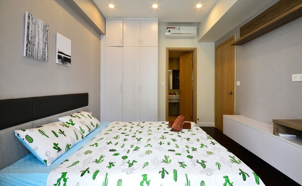 A bedroom with a bed, a wardrobe, a built-in bench, and a door leading to a bathroom.