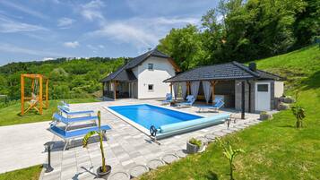 A modern house with a swimming pool, outdoor seating, and a garden.
