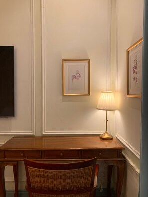 A wooden desk with a wicker chair, a framed floral artwork on the wall, and a standing lamp. - The Atlantic Langkawi (Langkawi)