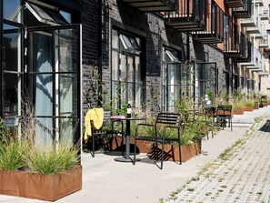 En række moderne bygninger med store vinduer og udendørs siddepladser.