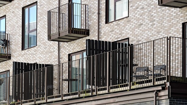 Un bâtiment moderne doté de nombreux balcons, de grandes fenêtres et d’une rangée de vélos garés à l’extérieur.
