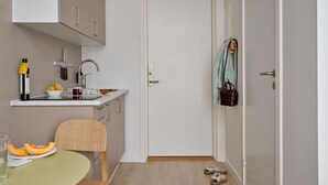 Une cuisine compacte comprenant un évier, un petit plan de travail et un coin repas avec une table et des chaises.