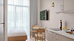 Habitació d'hotel moderna amb un llit, un escriptori amb un ordinador portàtil, una cadira, una taula petita amb un plat de fruita i xules sobre la llosa.